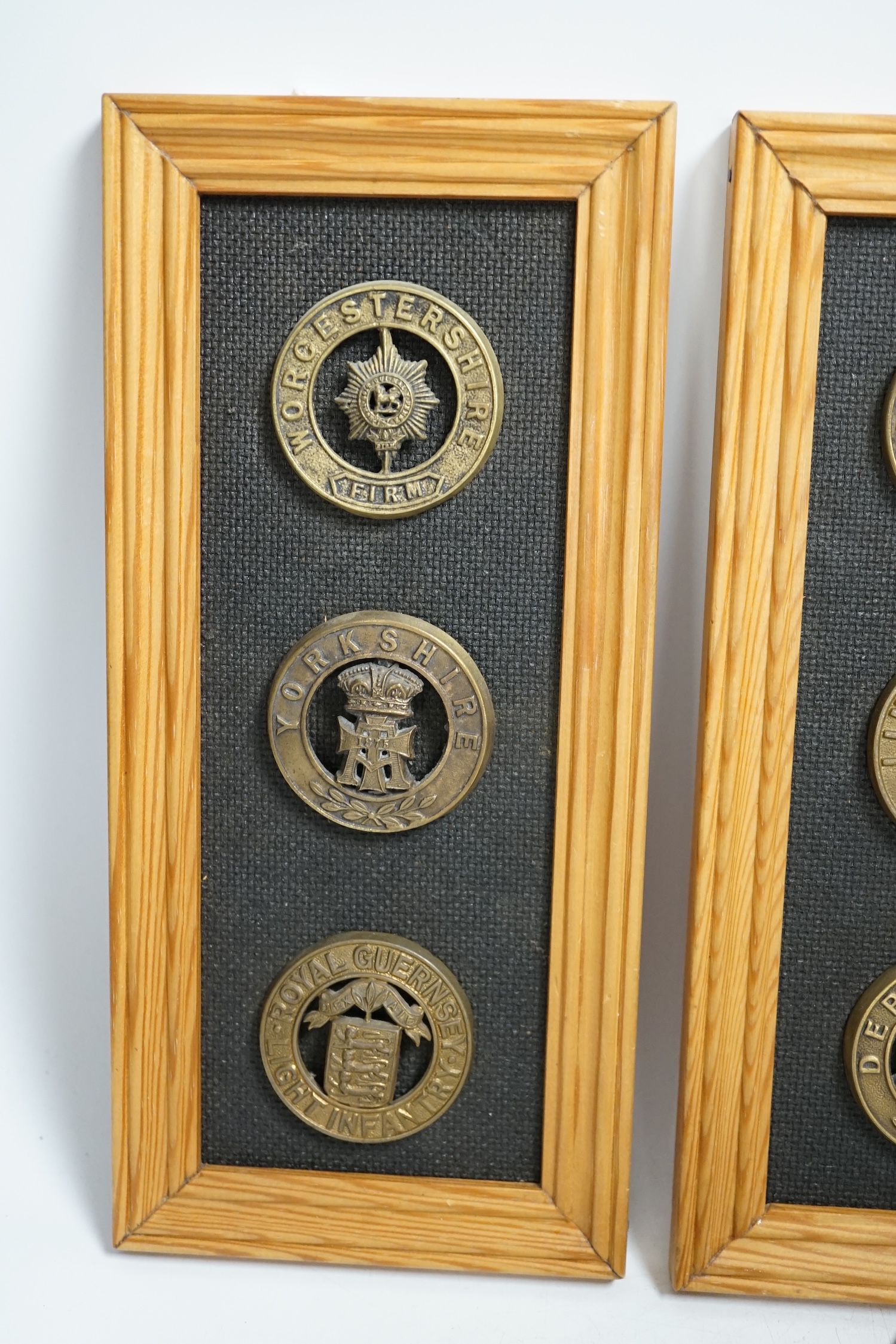 Six military helmet plates mounted on two boards, together with two helmet spikes and a cap badge, including; the Yorkshire Regiment, the Royal Guernsey Light Infantry, the Loyal North Lancashire, the Lincolnshire Regime